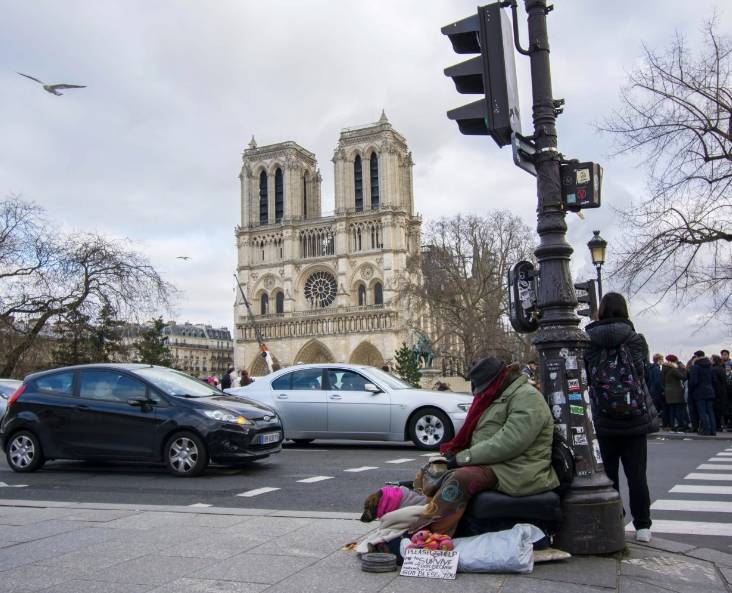 Un sans-abri avec son chien demande de l'argent devant la cathédrale Notre-Dame